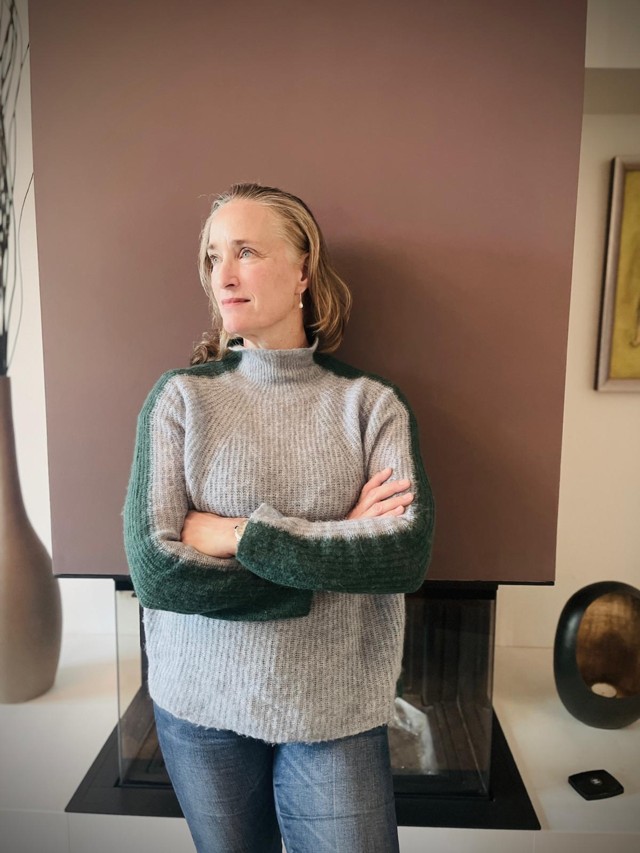 Adrienne Wright Bulow in ihrer Praxis, freundlich lächelnd, vor einem sanften Hintergrund – Symbol für persönliche Zuwendung und ganzheitliche Betreuung.